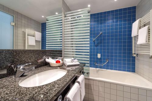 a bathroom with a sink and a tub at Dorint Hotel Potsdam in Potsdam