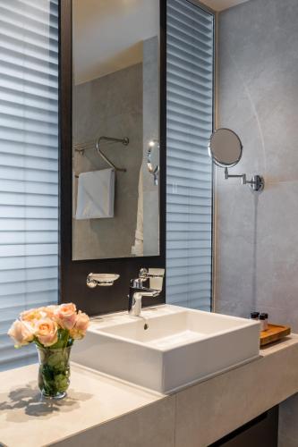 a bathroom with a sink and a vase of flowers at Derand Hotel in Pristina