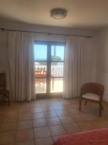 a room with a window with curtains and a chair at Siesta el por del sol in Santa Eularia des Riu