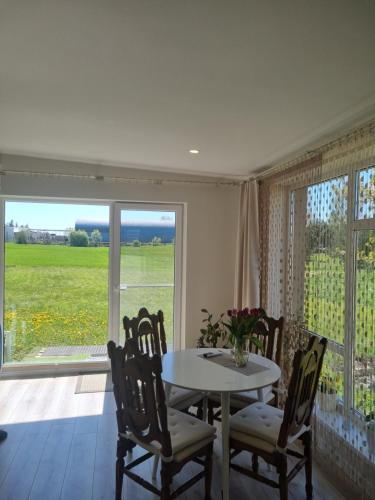 ein Esszimmer mit einem Tisch, Stühlen und einem Fenster in der Unterkunft Vilmos House in Vydmantai