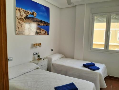 - 2 lits dans une chambre blanche avec une photo sur le mur dans l'établissement Apartamentos La Calilla Cabo de Gata, à Cabo de Gata