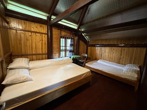 two beds in a room with wooden walls at SaPa Hmong Streamside Homestay in Sapa