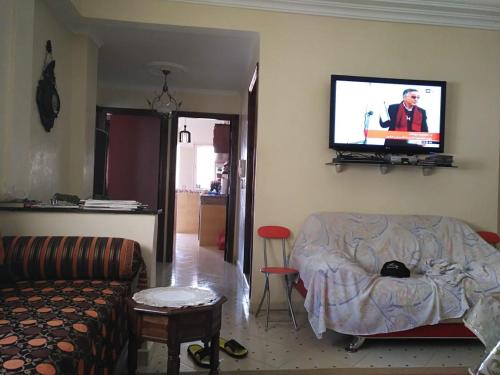 ein Wohnzimmer mit einem Sofa und einem Flachbild-TV in der Unterkunft Dream sun in Sidi Rahal