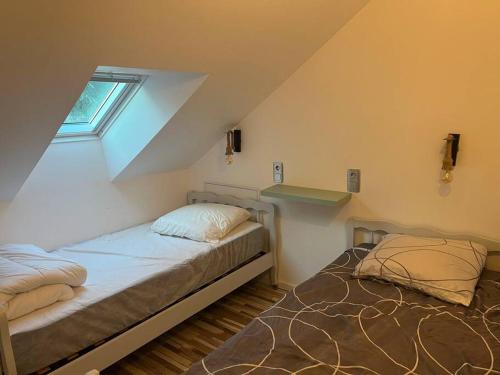 1 dormitorio en el ático con 2 camas y ventana en Gîte au 1er étage avec jardin en Azay-le-Rideau