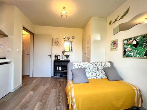 a bedroom with a yellow bed and a kitchen at Le Cosy, accès terrasse de l'établissement in Rives