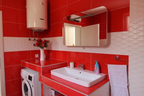 La salle de bains rouge est pourvue d'un lavabo et d'un miroir. dans l'établissement Skywalk House, à Mostar