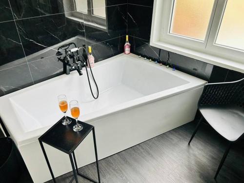 eine weiße Badewanne mit zwei Gläsern Wein in der Unterkunft Love room « L'étreinte dorée » in Illiers