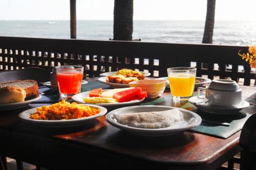 Una mesa con platos de comida y bebidas sobre ella. en Pousada Xalés de Maracaípe, en Porto de Galinhas