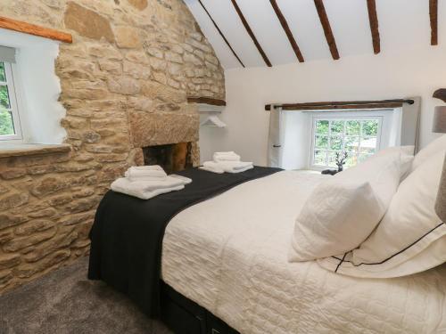 a bedroom with a large bed with a stone wall at Lydgate Cottage in Eyam