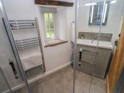 ein Bad mit einer Dusche und einem Waschbecken in der Unterkunft Lydgate Cottage in Eyam