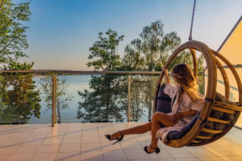 a woman sitting in a swing on a house overlooking the water at Willa Port in Ostróda