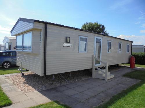 a tiny house sitting in a yard with a driveway at Kingfisher : Seasons:- 8 Berth, Central Heated, Close to site shop in Ingoldmells