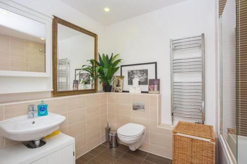 a bathroom with a sink and a toilet and a mirror at Unique & Welcoming 2BD Flat in Limehouse in London