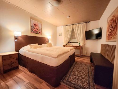 a bedroom with a large bed and a television at Landhaus Kürrenberg in Mayen
