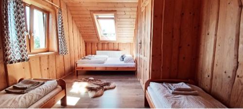 a room with two beds in a wooden cabin at Domek na Przełęczy in Ochotnica Górna