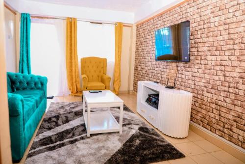 a living room with a couch and a tv on a brick wall at A&T Luxury Homestays in Kisii