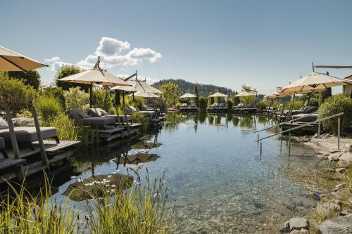 a pool of water with chairs and umbrellas at Wellness- & Sporthotel Jagdhof in Röhrnbach