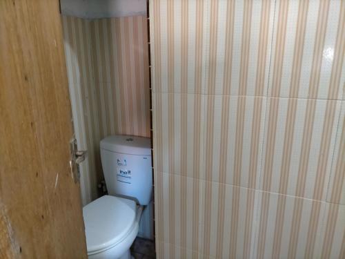 a bathroom with a toilet and a wooden door at Merpati Hostel Banyuwangi in Dadapan