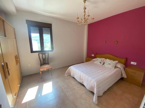 a bedroom with a bed and a pink wall at La cerrada in El Collado