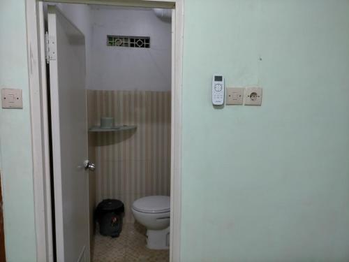 a bathroom with a toilet and a door open at Merpati Hostel Banyuwangi in Dadapan