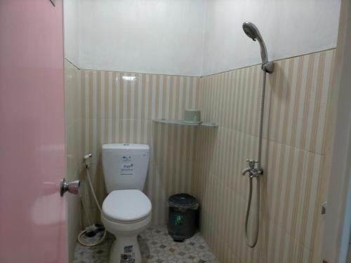 y baño pequeño con aseo y ducha. en Merpati Hostel Banyuwangi, en Dadapan