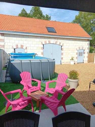 four pink chairs and a table in front of a pool at Superbe gite familial pour 10 personnes à Gizeux in Gizeux
