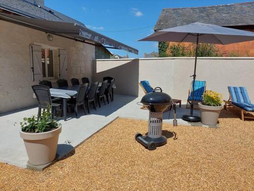 a patio with a table and an umbrella and chairs at Superbe gite familial pour 10 personnes à Gizeux in Gizeux