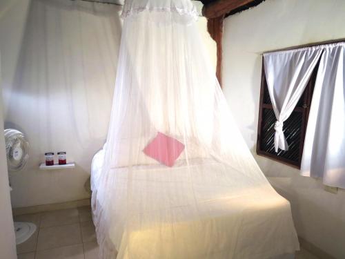a bedroom with a white bed with a window at Palomino Breeze Hostal in Palomino