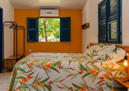 1 dormitorio con 1 cama con colcha tropical en Éden do Catu en Aquiraz