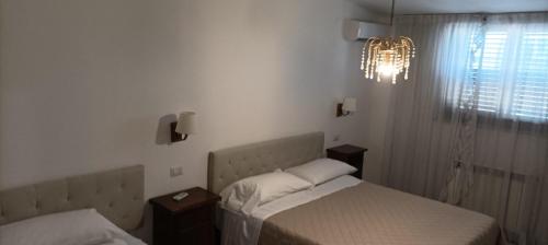 een slaapkamer met 2 bedden en een kroonluchter bij rooms speedy vicino aeroporto e fiera di roma in Fiumicino