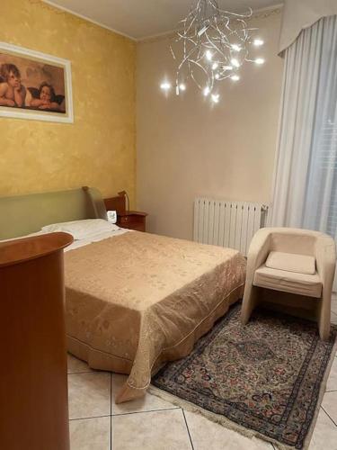 a bedroom with a bed and a chair and a chandelier at Casa Appennini in Licata