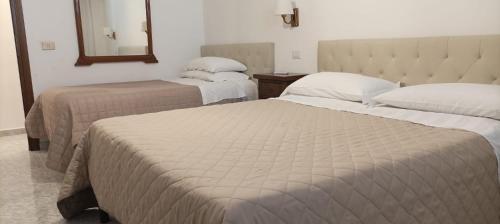 Habitación de hotel con 2 camas y espejo en rooms speedy vicino aeroporto e fiera di roma, en Fiumicino