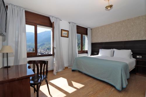 a bedroom with a bed and a desk and windows at Hotel Blu Aran in Vielha