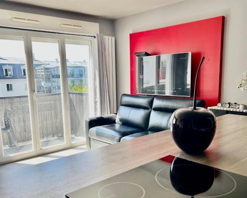 een woonkamer met een zwarte stoel en een rode muur bij Cosy apartment Disneyland Paris en face de la gare RER val d'Europe in Serris