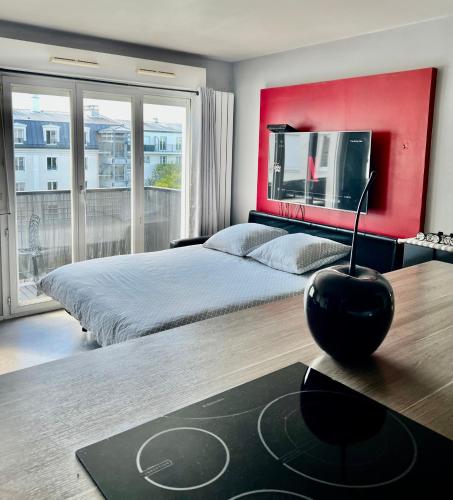 une chambre avec un grand lit avec un mur rouge dans l'établissement Cosy apartment Disneyland Paris en face de la gare RER val d'Europe, à Serris