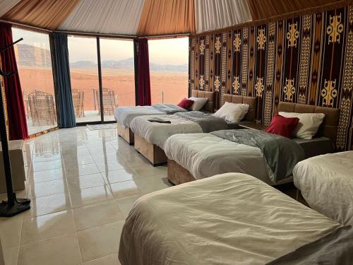 four beds in a room with large windows at Wadi Rum Desert Adventures in Wadi Rum