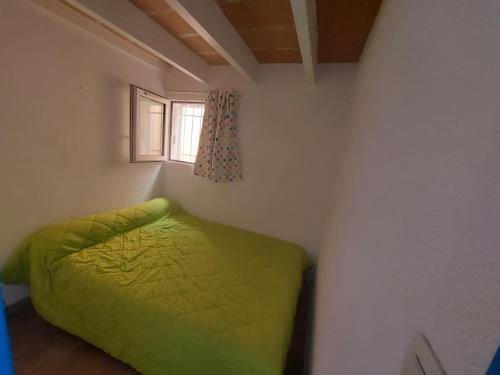 une chambre avec un lit vert et une fenêtre dans l'établissement VILLA AU LES VILLAGEOISES II, à Marseillan
