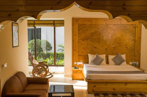 a bedroom with a bed with a large wooden headboard at The Roar Resort in Rāmnagar