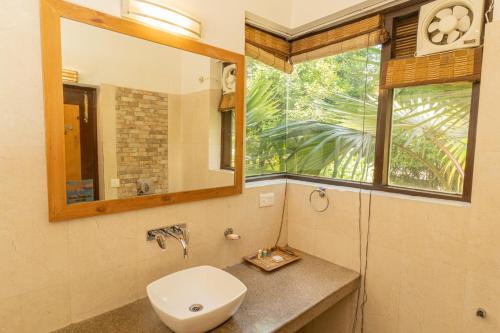 a bathroom with a sink and a mirror and a window at The Roar Resort in Rāmnagar