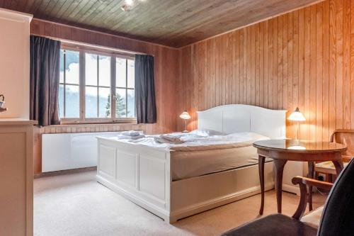 Schlafzimmer mit einem Bett, einem Tisch und einem Fenster in der Unterkunft Apartment Zita - GRIWA RENT AG in Grindelwald