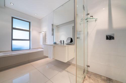 a white bathroom with a shower and a window at Amara Lincoln - 100m From Camps Bay Beach in Cape Town