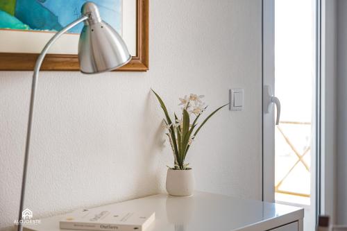 Un escritorio blanco con una lámpara y flores. en The Pateo Beach Apartment - Santa Cruz, en Santa Cruz