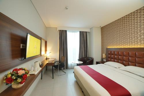 um quarto de hotel com uma cama e uma secretária com flores em Pakons Prime Hotel em Tangerang