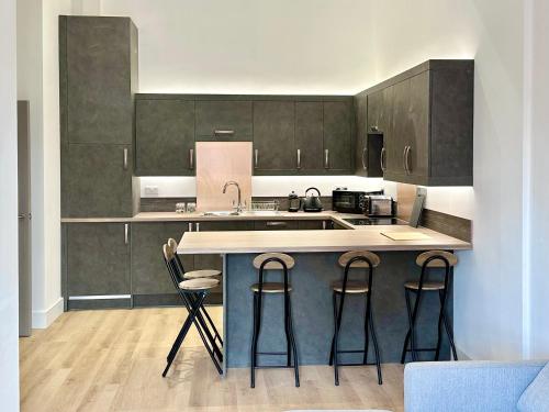 a kitchen with a island with three bar stools at Fountain Apartment No 2 with Free Parking in York
