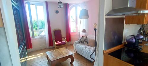 - un salon avec un canapé et quelques fenêtres dans l'établissement Charmant 40m2 a 2 pas de la mer, à Saint-Aubin-sur-Mer