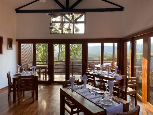 a dining room with tables and chairs and windows at Lilac Hideaway in Karatu