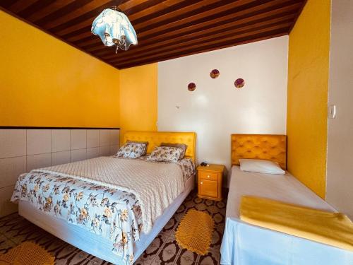 two beds in a room with yellow walls at Hospedagem Serra da Lua in Alter do Chao