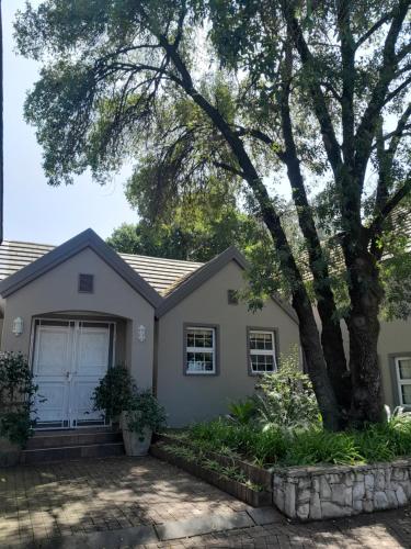 a house with a tree in front of it at Sugarbush Accommodation in Vereeniging