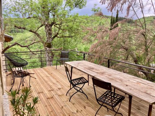 un tavolo e sedie in legno su una terrazza di legno di Molinot chambres d'hôtes a Alboussière