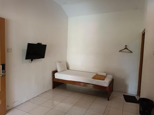 a small white room with a bed and a tv at Hotel Maerakatja Yogyakarta in Jetis